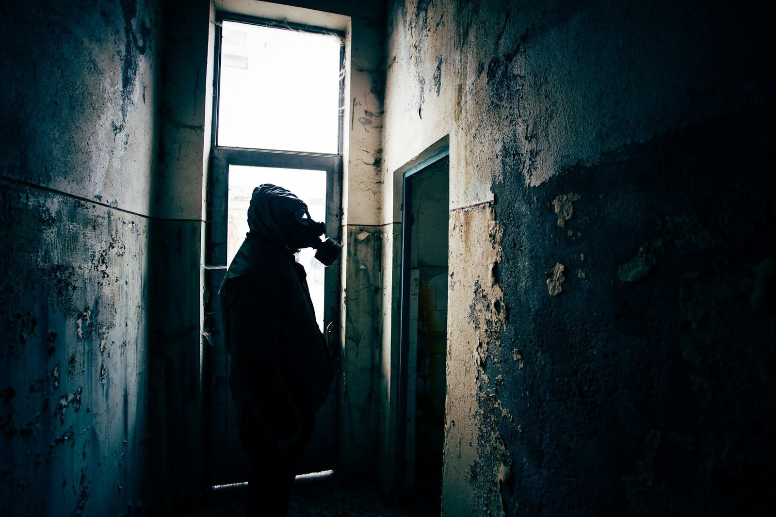 Silhouette of a man wearing a gas mask in a bombedbuilding.
